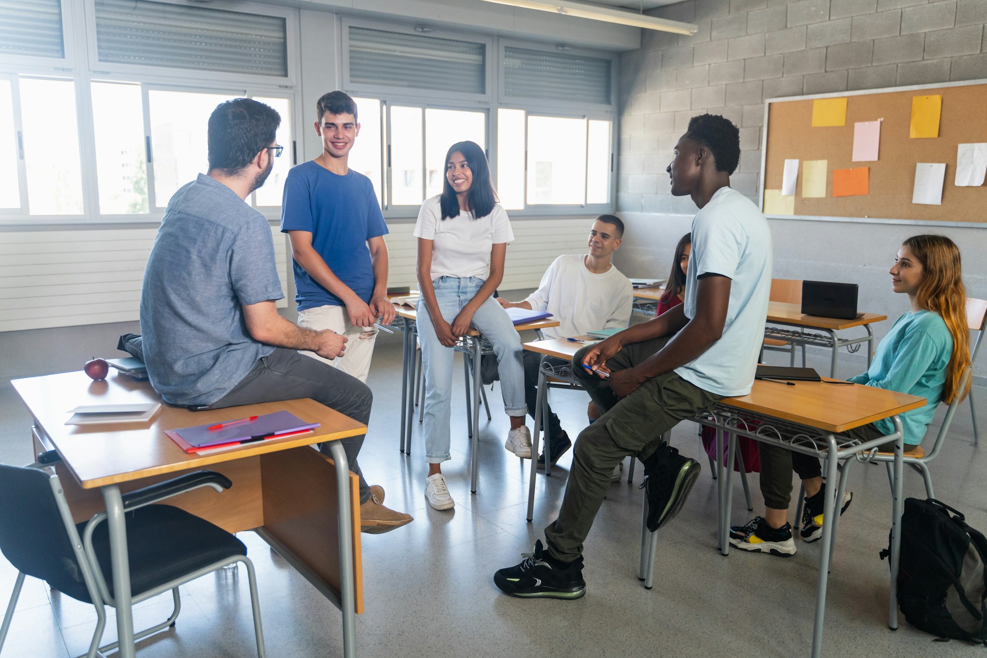 Students and young teacher having a conversation at classroom