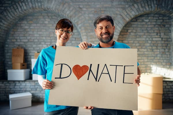 Mężczyzna i kobieta trzymający baner z angielskim napisem Donate